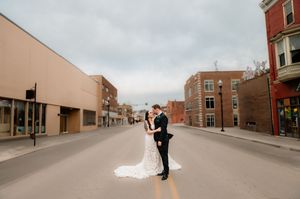 Panoramic street view of couple in urban setting with brick buildings and overcast sky.