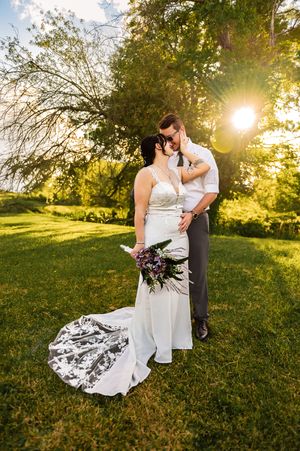 Wedding couple shares intimate moments at sunset in grassy field.