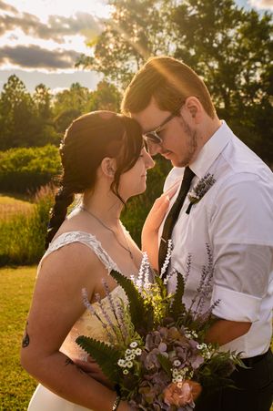Romantic sunset wedding photos showing couple embracing with floral bouquet in golden hour lighting.