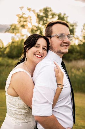 Happy wedding couple shares joyful laughter in golden evening light.
