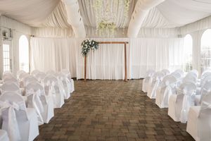 White draped wedding venue interior with elegant chair covers and romantic ceiling decorations.