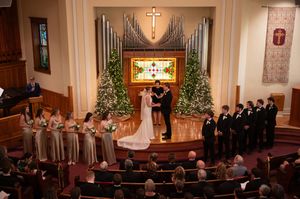 Traditional church wedding ceremony with decorated altar, organ pipes, and Christmas trees.