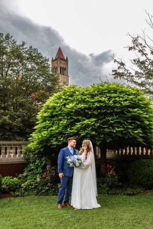 A romantic garden wedding scene with vibrant greenery and a church spire in the background.