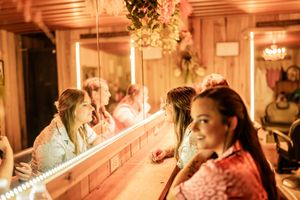 Warm-lit rustic barn wedding celebration with ambient lighting and decorative greenery along wooden beams.