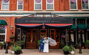 Historic red brick building with patriotic bunting decorations and green awnings on a downtown street.