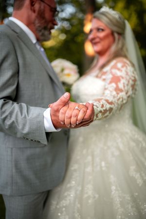 A couple holds hands during their outdoor wedding ceremony with beautiful natural lighting.