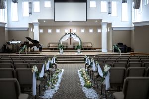 Church sanctuary decorated with white flowers and fabric along the aisle for an elegant wedding ceremony.