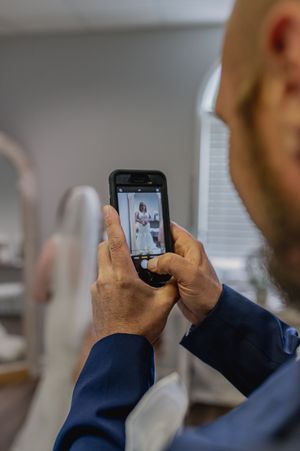 Person using smartphone to take photos in bright indoor setting while wearing navy blue attire.