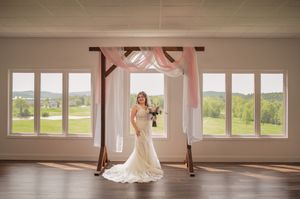 A bride stands in an elegant venue space framed by pink and white draped fabric.