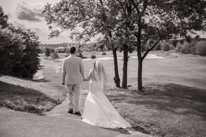 Wedding party walking through a scenic hillside path with trees and green landscape.