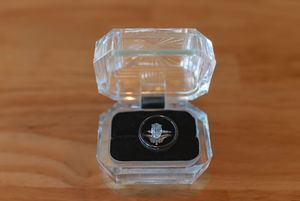 Clear glass ring box with wedding bands displayed on wooden surface.