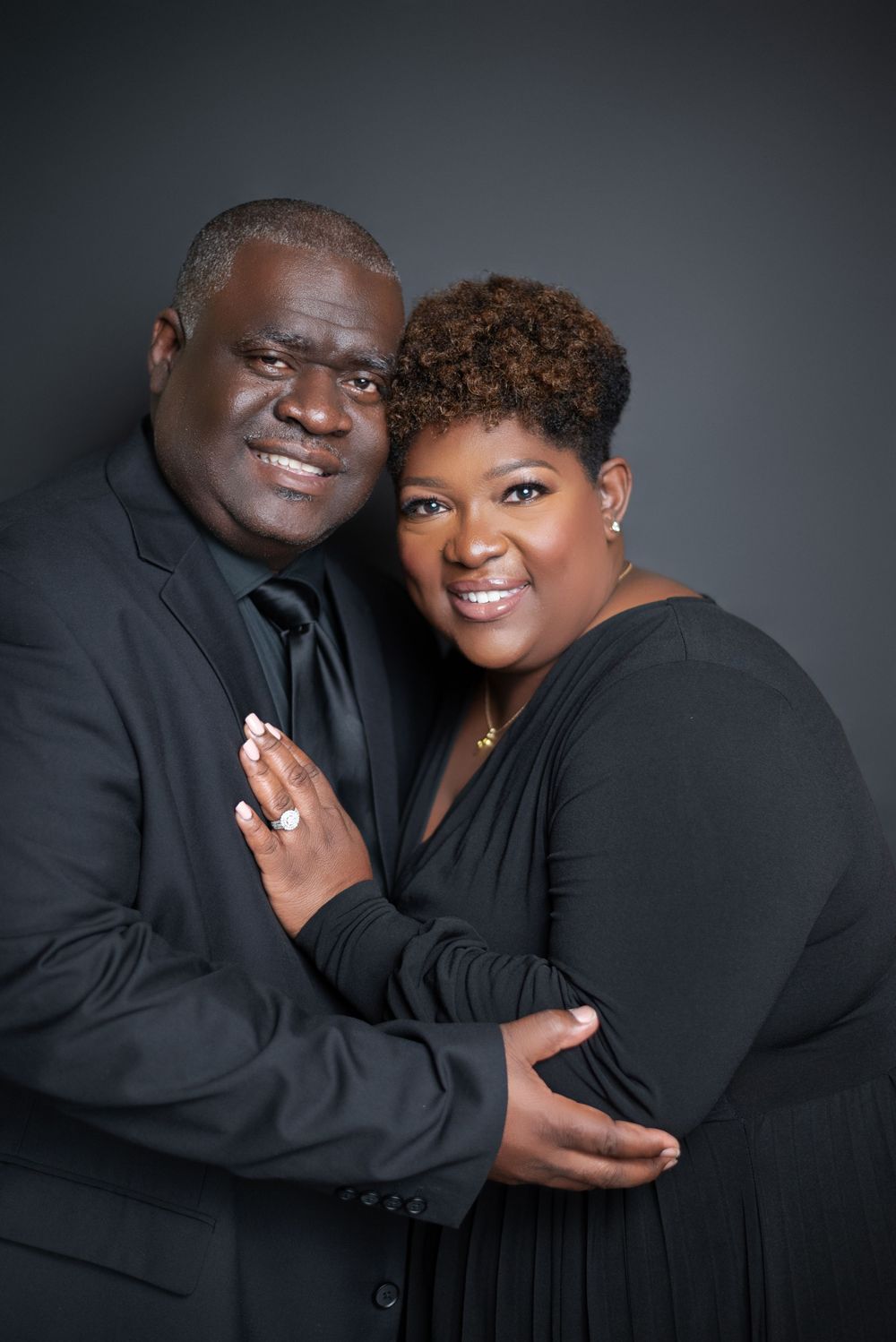 Romantic couple portrait session against dark background showing affectionate poses.