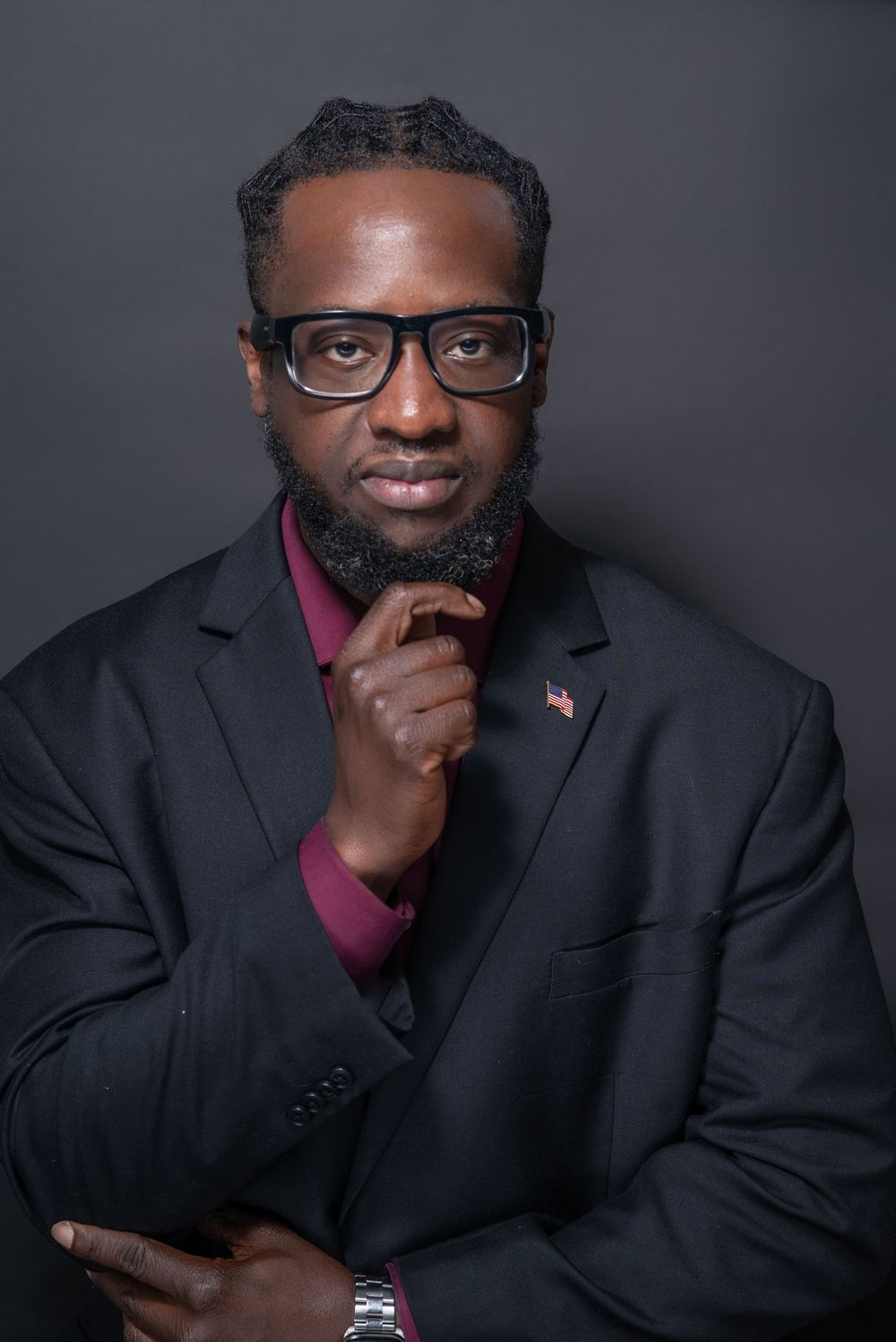 Professional portrait series in dark setting showing contemplative poses against gray background wearing black suit.