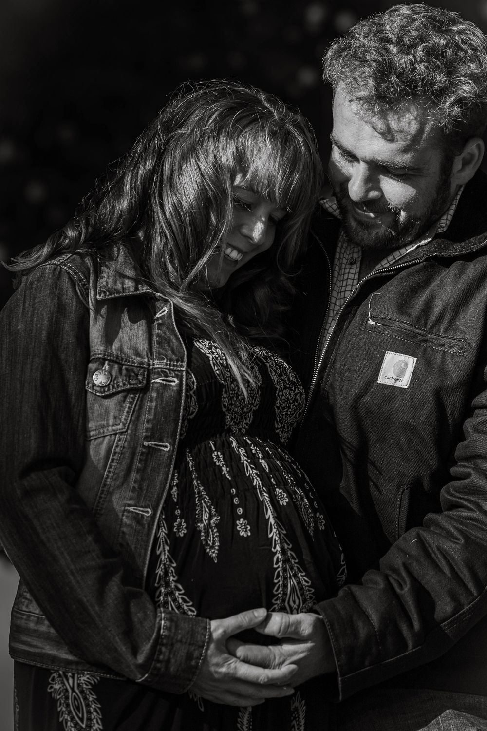 A black and white intimate maternity portrait captures a tender moment between an expectant couple.