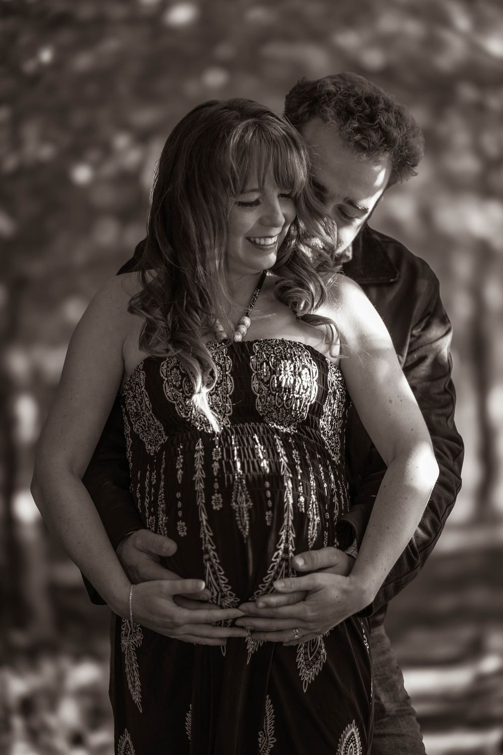 An intimate black and white maternity portrait captured in natural outdoor setting.
