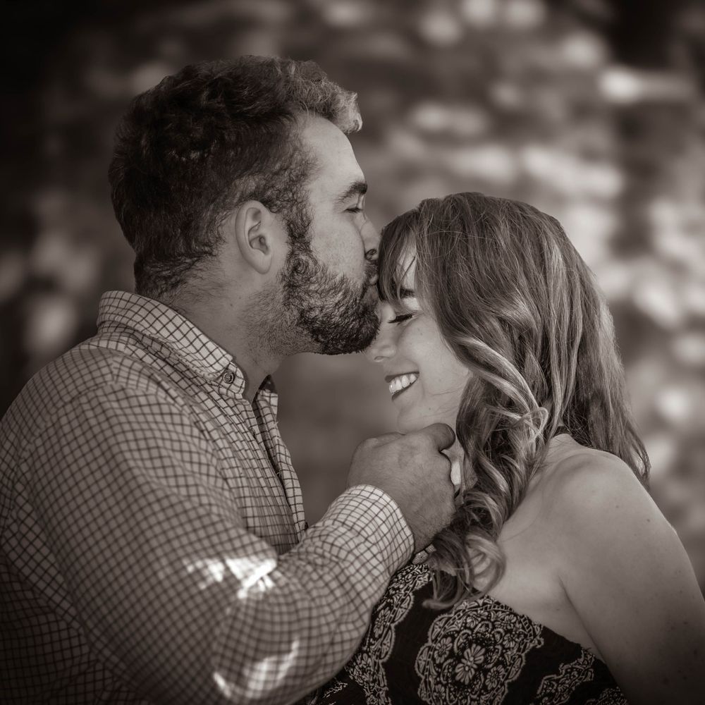 A close-up black and white photo captures a tender moment between an expectant couple.