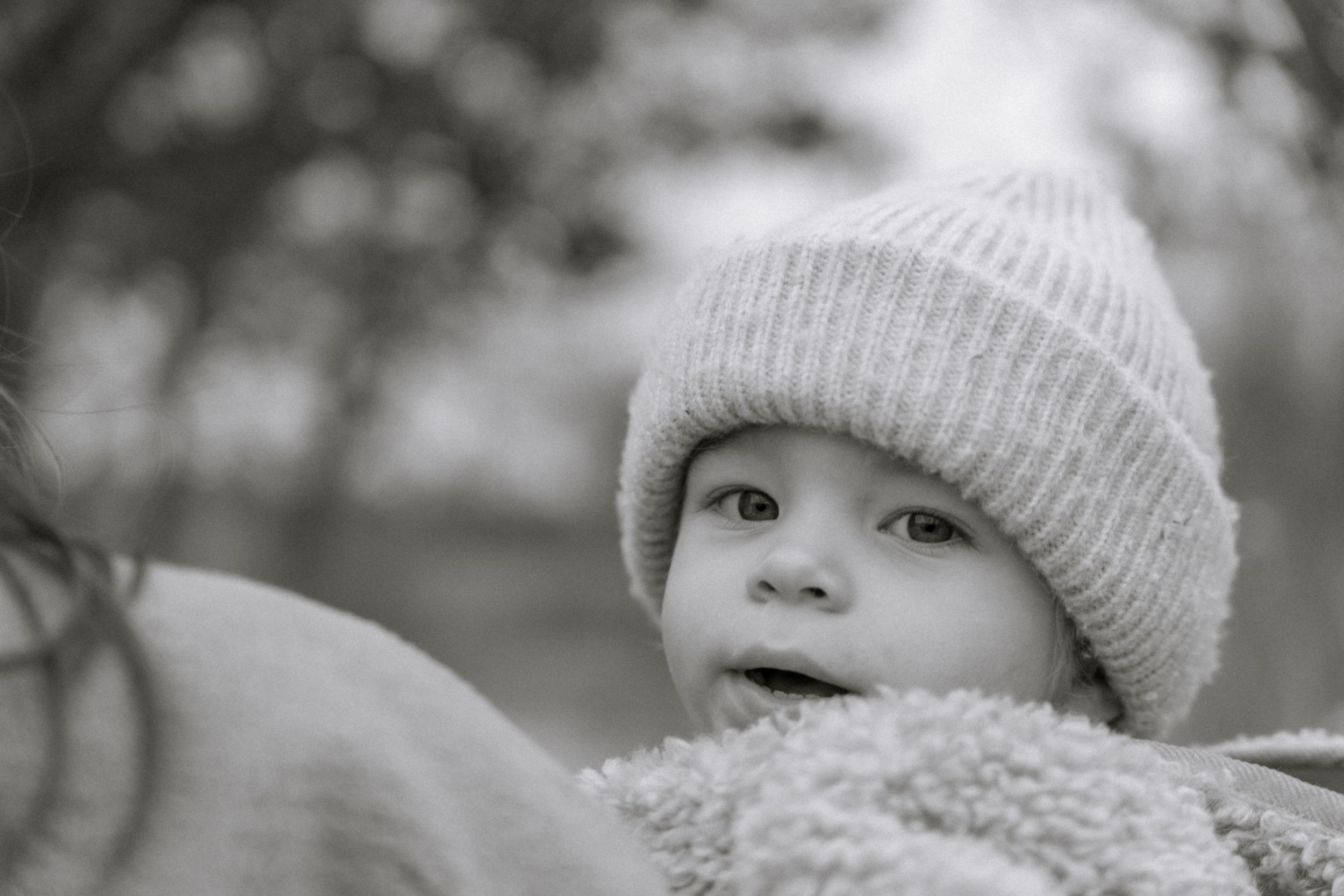 Black and white portrait of a young child wearing a warm knit beanie and cozy winter clothing.