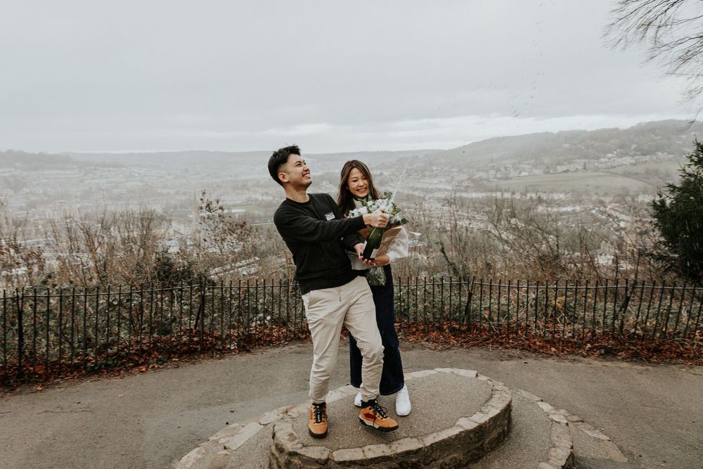 Surprise proposal in Bath , Alexandra Park with stunning views and champagne spray celebration  photos . Happy couple just proposed