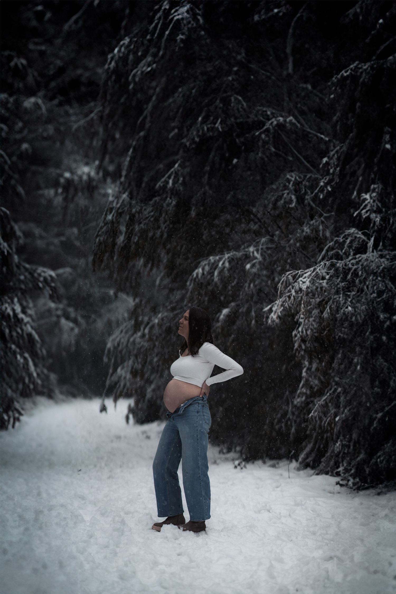 Person in winter attire embraces another in snowy forest setting.