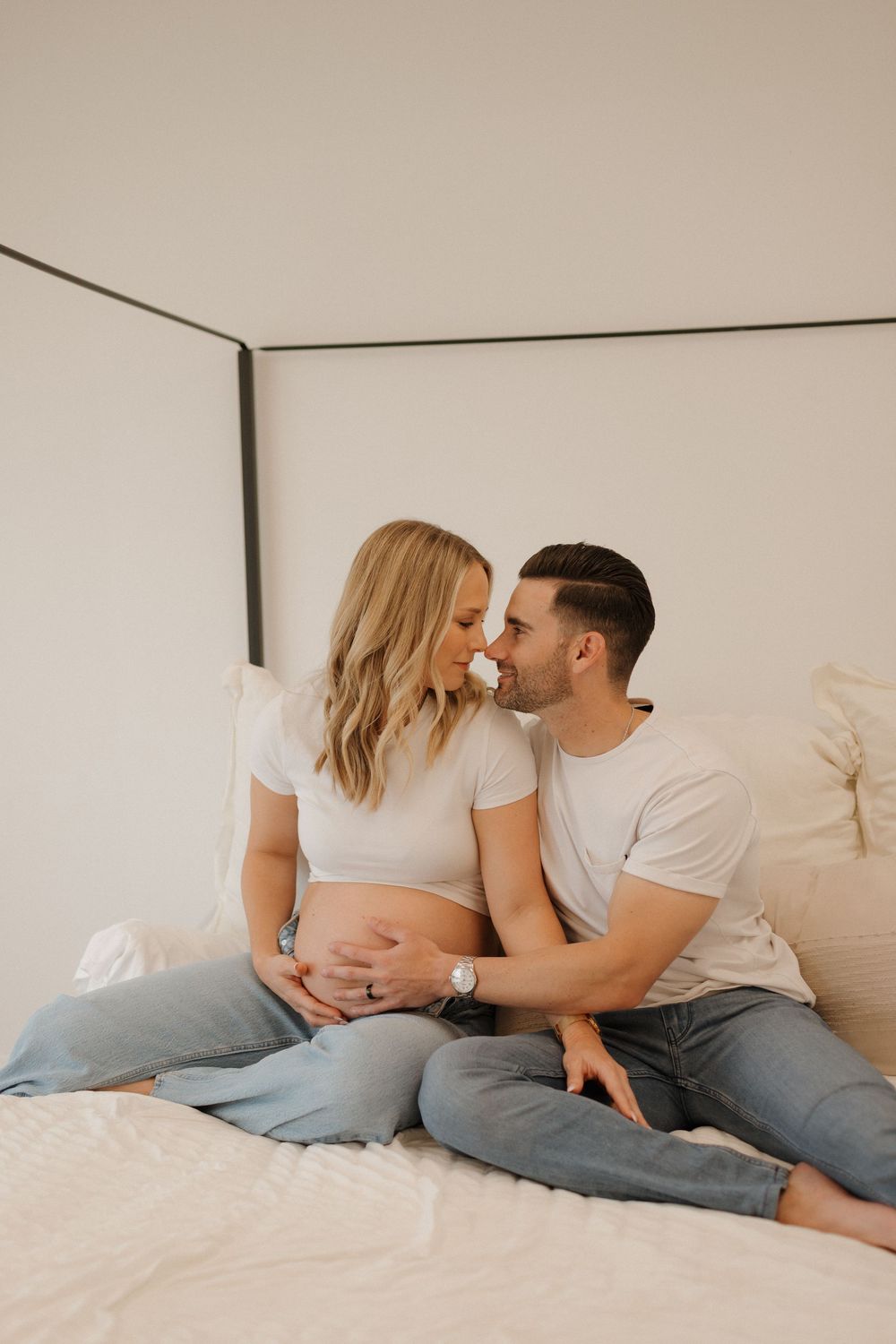 Intimate maternity photo of couple sharing tender moment on bed.