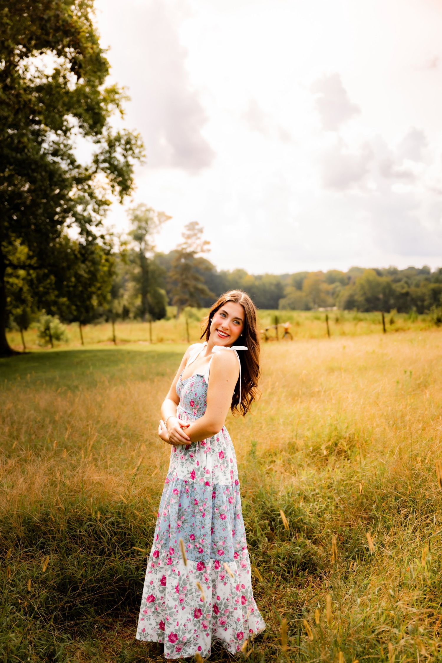 A floral maxi dress catches the golden light in a dreamy meadow photoshoot at sunset.