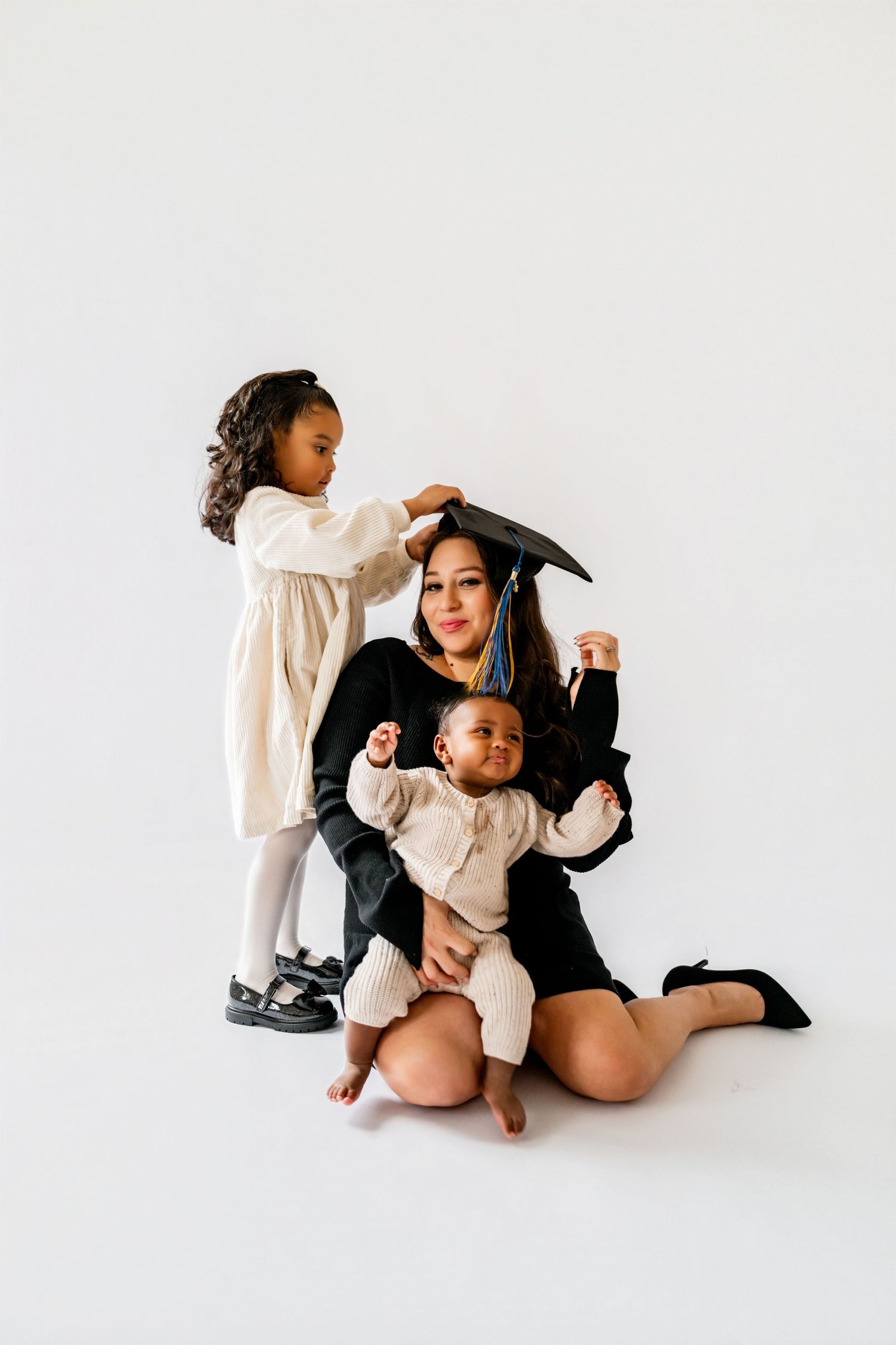 Family portrait session on white backdrop showing playful interaction.