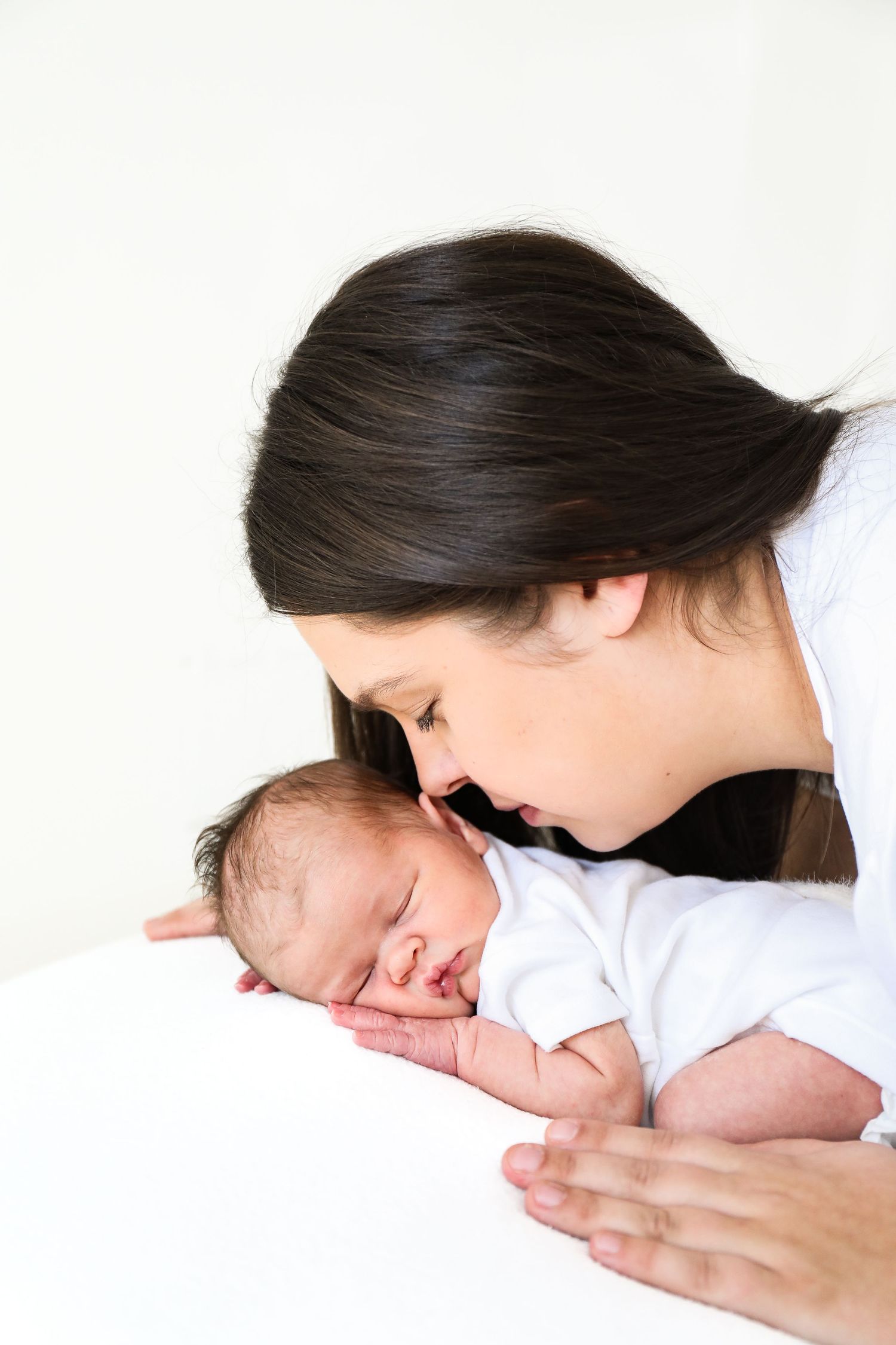 A tender moment between a parent and sleeping newborn baby, creating an intimate portrait, during newborn shoot in Nottingham