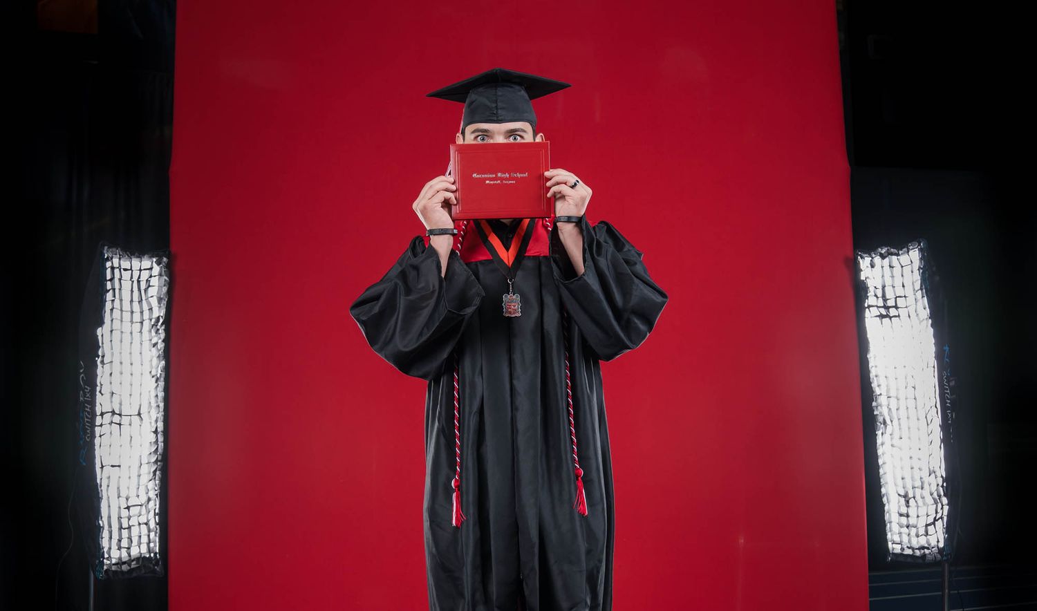 CHS graduate poses for 2025 Coconino High School commencement, covering his face during photos by Sean Openshaw Photography.
