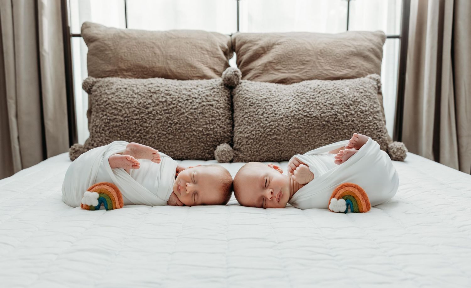 Adorable newborn twins in matching rainbow outfits lying side by side on a white bed.
simple timeless natural