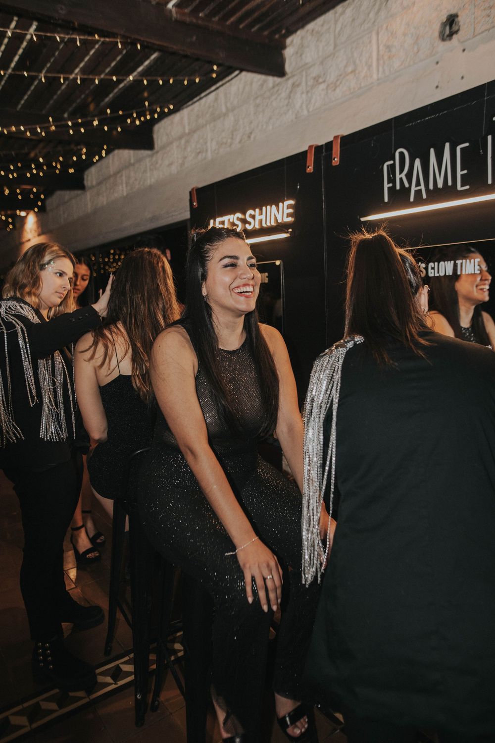 Grupo de amigos en lugar con luces colgantes, disfrutando la noche, ideal para stand de glitter y glitter bar para eventos y fiestas.