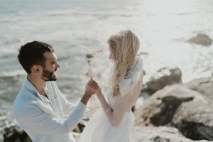 Bride picking wildflowers from rocks — natural beach elopement detail.