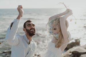Bride picking wildflowers from rocks — natural beach elopement detail.