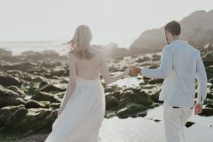 Intimate elopement photoshoot on a beach in Portugal with barefoot couple at sunset.