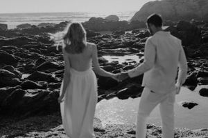 Intimate elopement photoshoot on a beach in Portugal with barefoot couple at sunset.