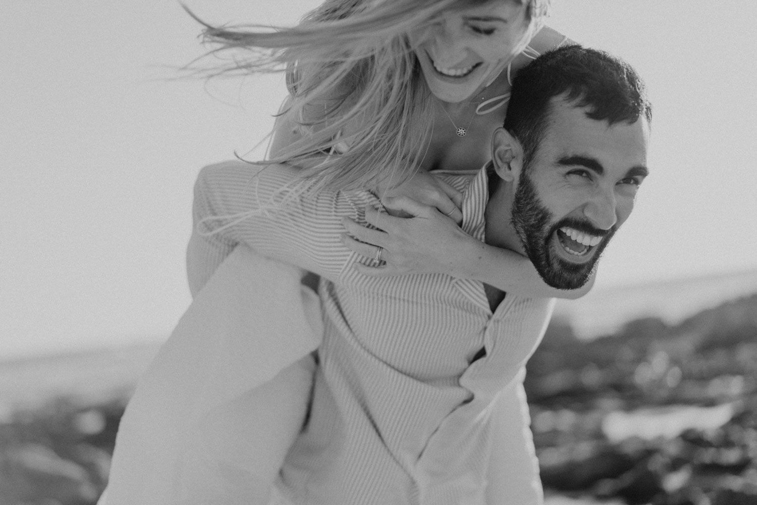 Elopement couple walking barefoot on a beach in Portugal — wild, intimate moment by the ocean.