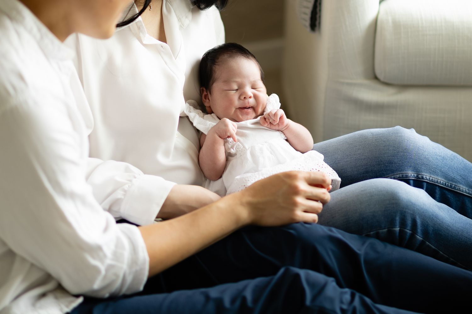 New mom and dad sit on their nursery floor holding their new baby girl during their in-home lifestyle newborn session in Tehaleh.