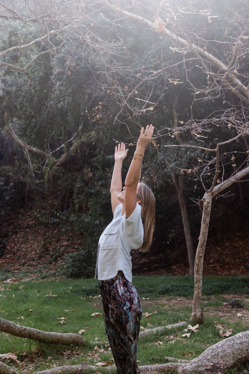 Woman reaches upward in nature during yoga flow — garden wellness photography by Adrian Rudd Kahn.