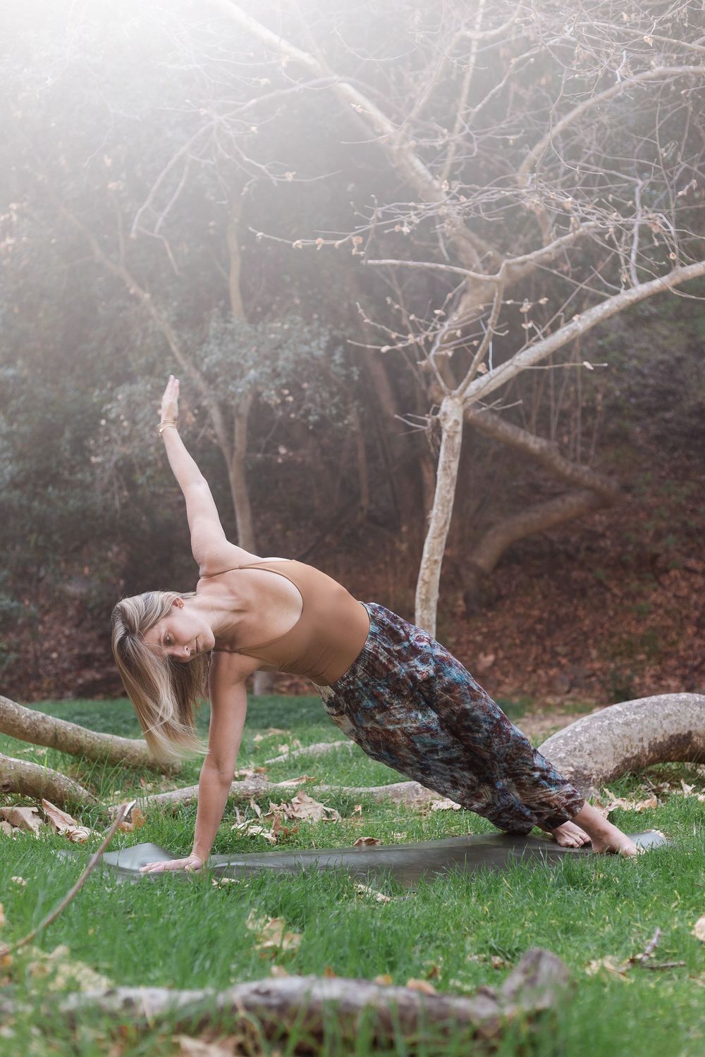 Side plank yoga pose in patterned pants outdoors — mindful movement photo by Adrian Rudd Kahn.