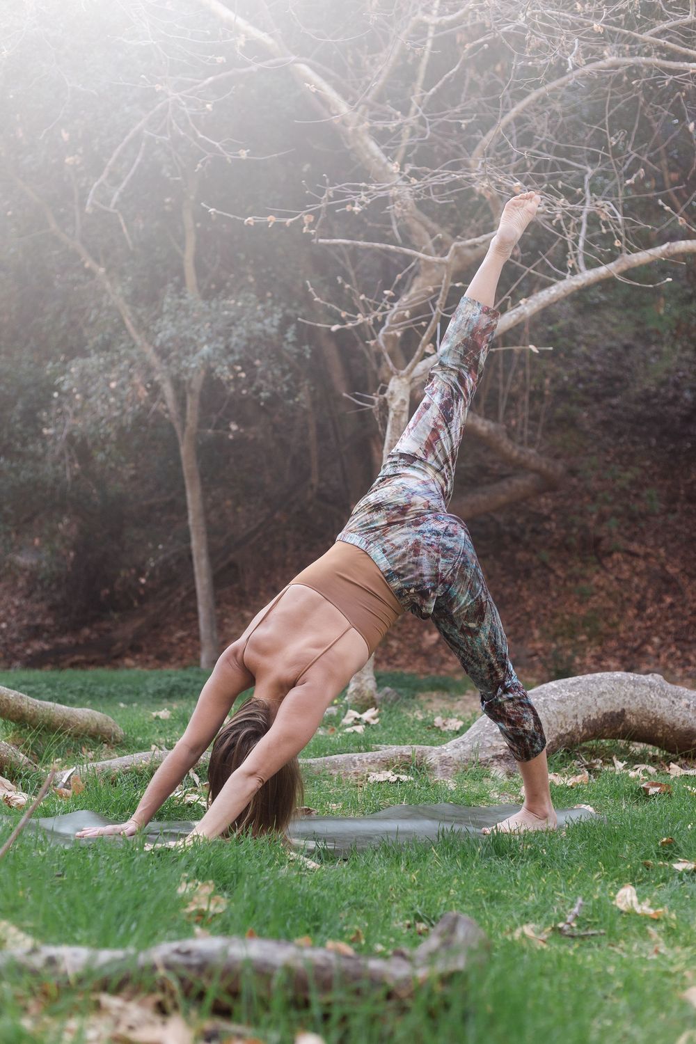 Handstand yoga pose on grass in woodland light — outdoor wellness photography by Adrian Rudd Kahn.