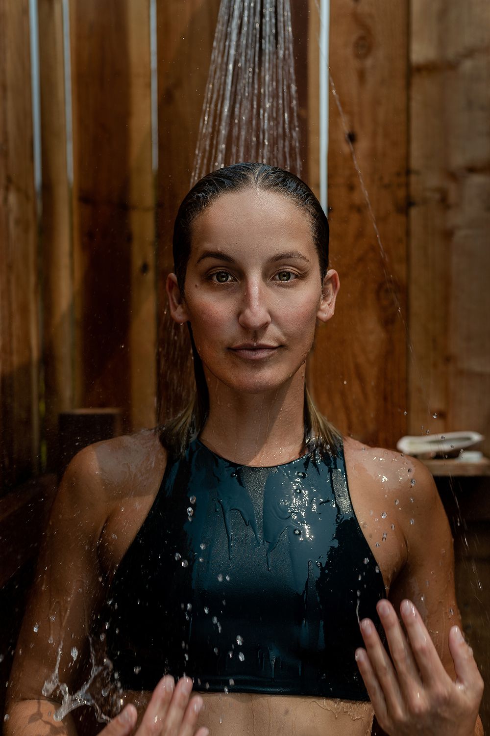 Woman showering outdoors in athletic wear — wellness lifestyle photography by Adrian Rudd Kahn.