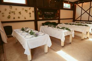 Long white banquet tables arranged in a room with decorative wall accents for an elegant event setup.