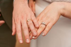 Close-up of wedding rings and hands showcasing engagement and wedding bands.