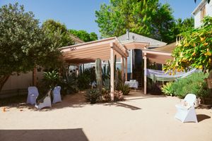Desert garden wedding venue with wooden pergola, cactus plants and white chairs set up for an outdoor ceremony.