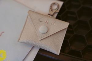 Small beige leather envelope keychain wallet with snap closure.