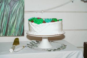 White wedding cake with green floral decorations displayed on a cake stand.
