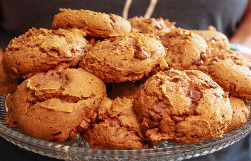 Golden brown cookies with chocolate chips stacked on a crystal serving plate.