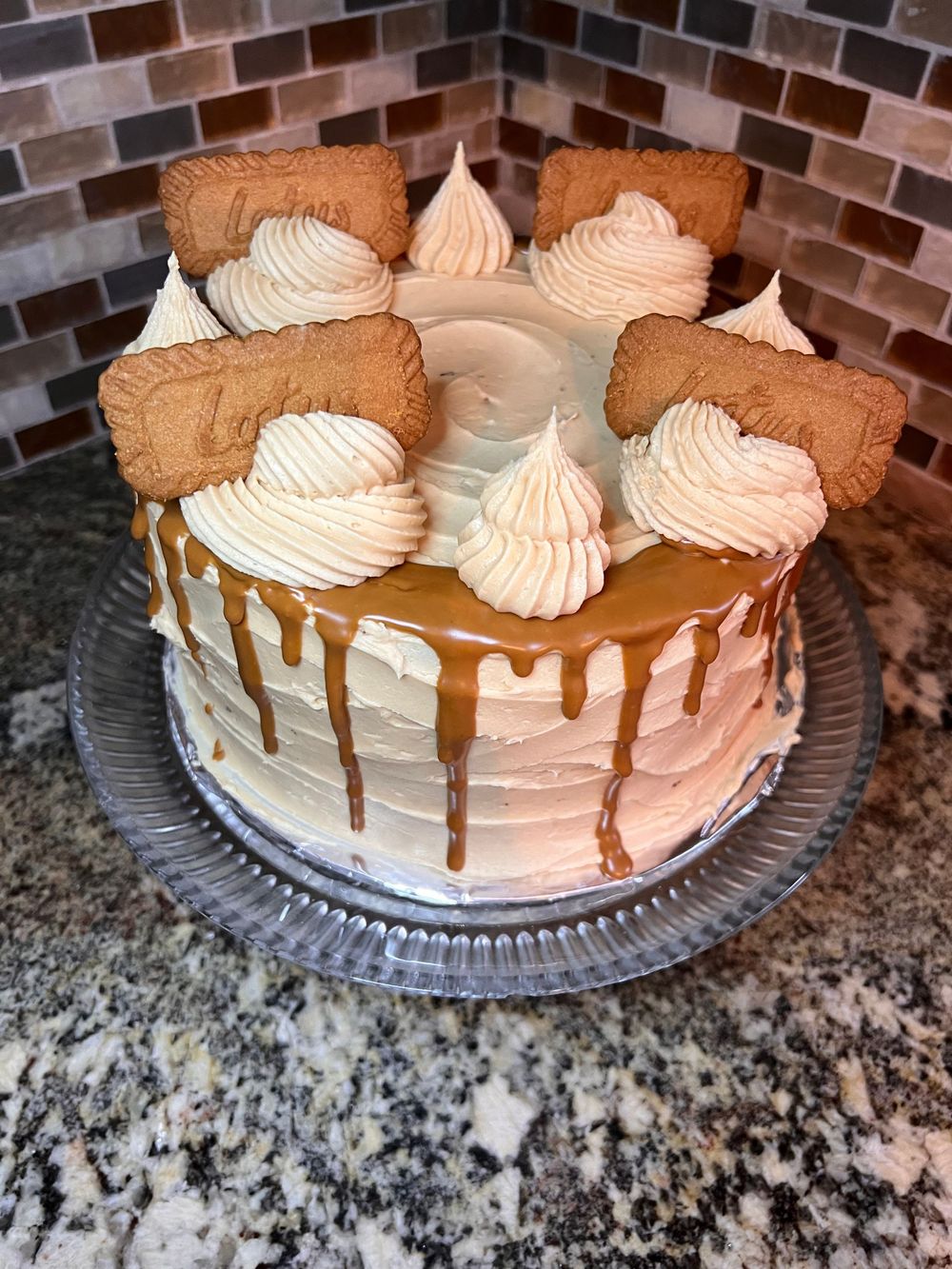 White frosted layer cake decorated with cookie pieces and caramel drips.