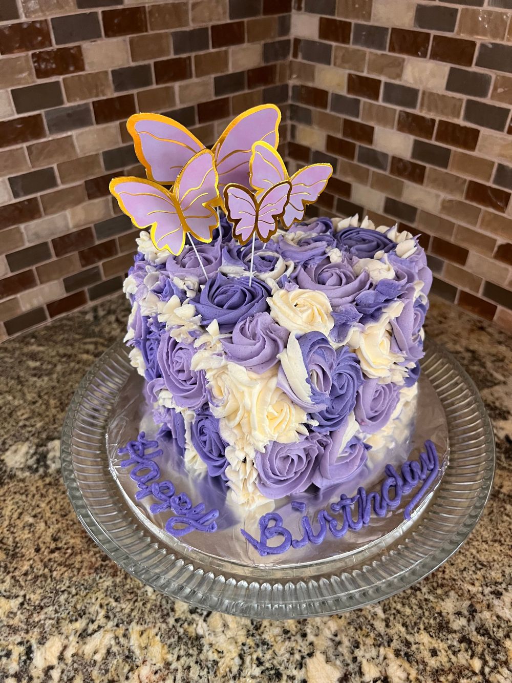Purple and white swirled buttercream cake decorated with purple butterfly toppers.
