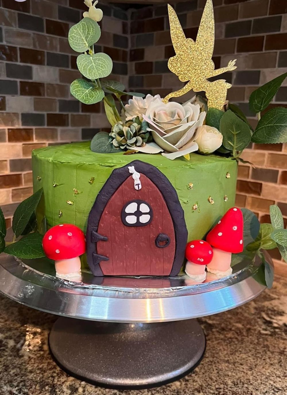 Whimsical fairy garden cake with green frosting, mushrooms and golden fairy silhouette.