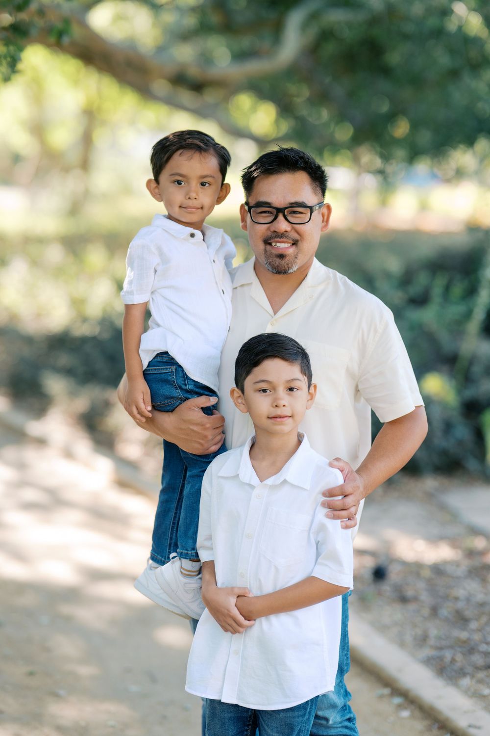 Four similar outdoor family portraits taken in a wooded setting show warm interaction and matching white shirts.